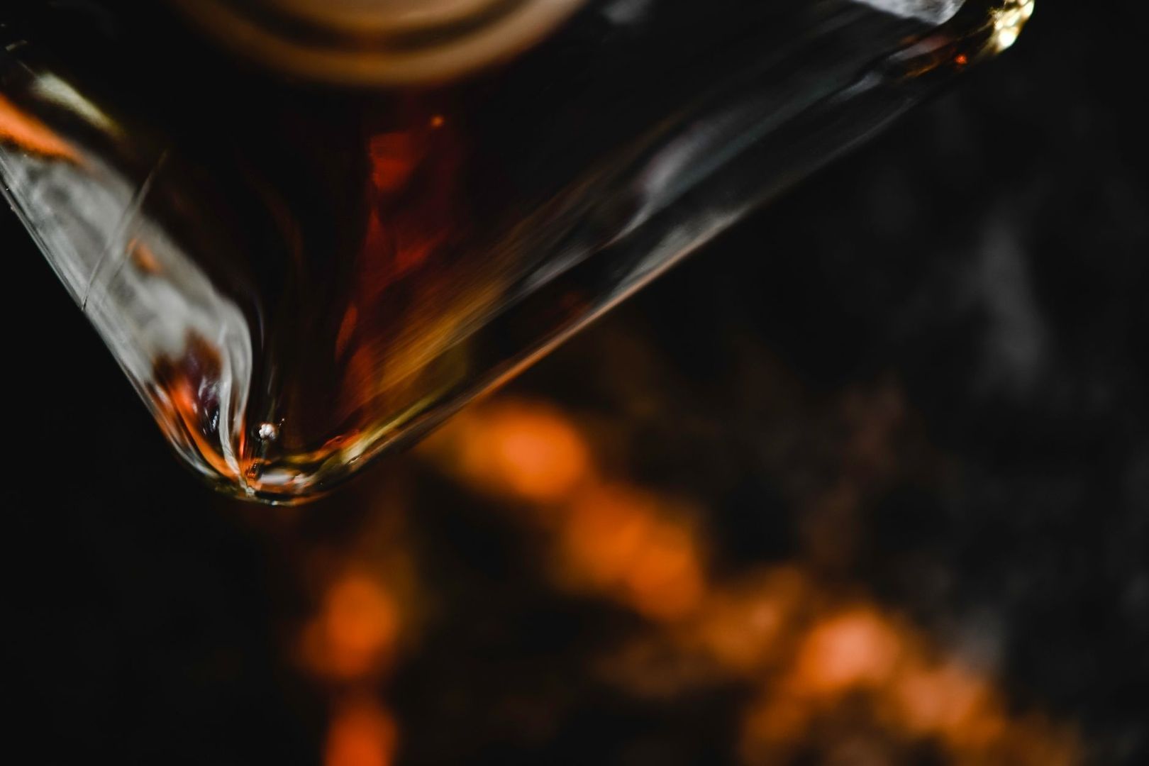 Närbild av en whiskyflaska i dunkelt ljus med varm bärnstensfärgad glans